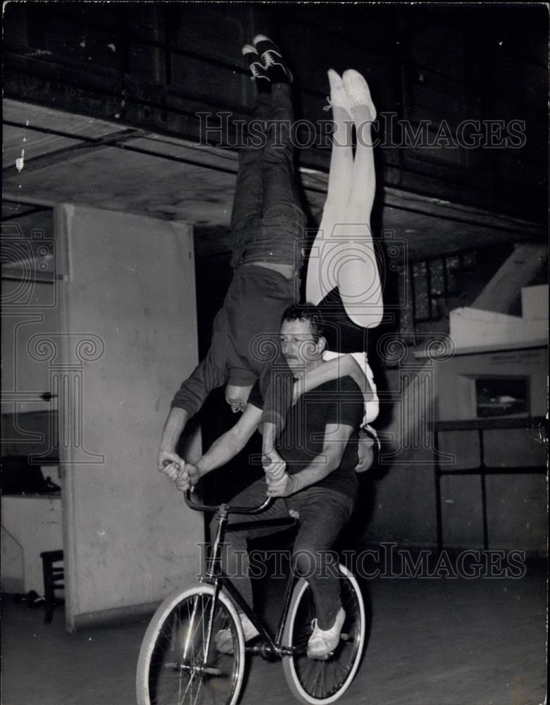 Press Photo Man Rides Bike With Two People Standing Upside Down On Him And Bike - Historic Images