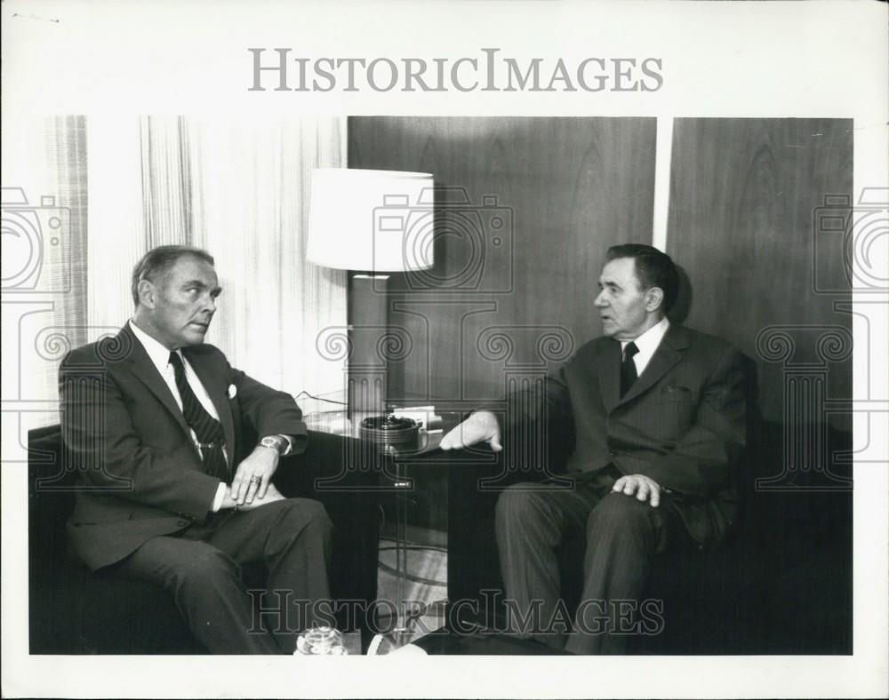 Press Photo Two Men Look At Each Other From Their Chairs - Historic Images