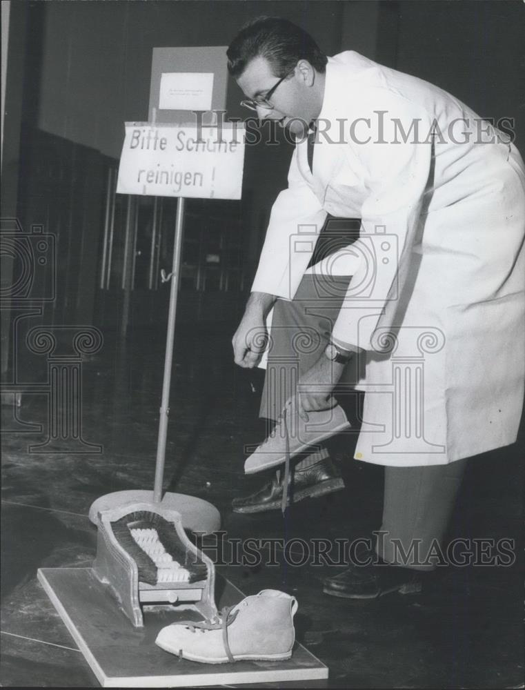 Press Photo Man changes shoes to keep safe - Historic Images