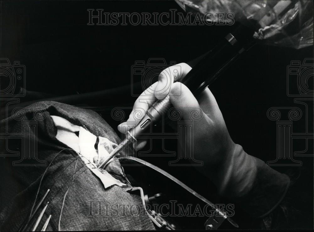 Press Photo Man Working On Some Mechanical Item With Cloth Over It - Historic Images