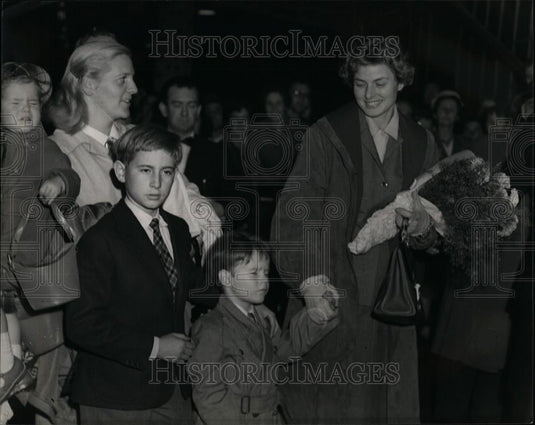 Press Photo A Woman Carrying Flowers Holds A Child's Hand - Historic Images