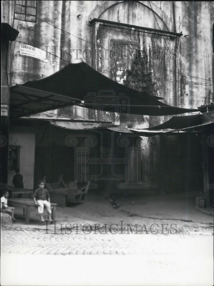 Press Photo A Child Sits On A Table Outside - Historic Images