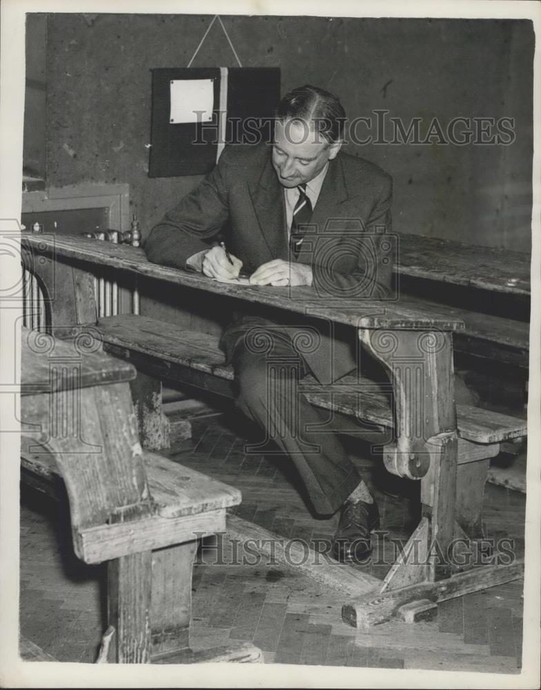 1957 Press Photo headmaster Mr. Mark Wheeler, sits at the desks at Cheam School - Historic Images