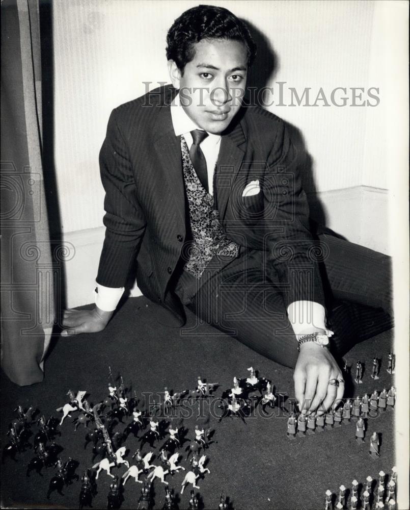 Press Photo man in suit sitting on floor with figurines - Historic Images