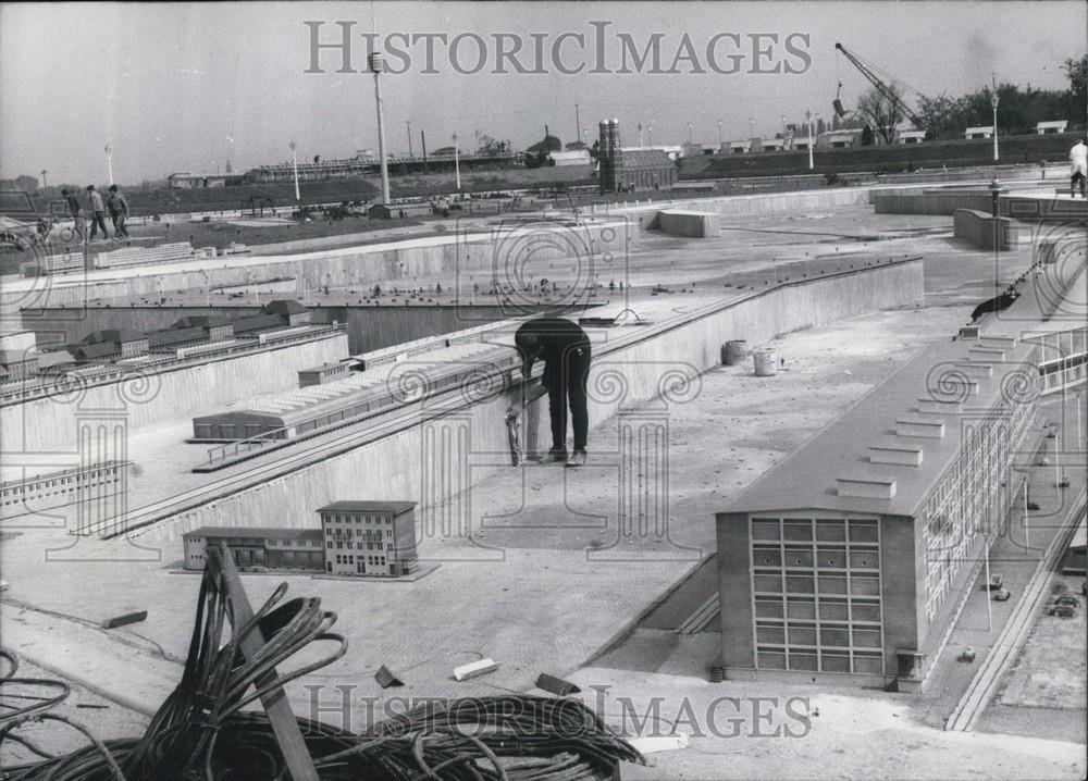 Press Photo man with miniscale buildings near field of airplanes - Historic Images