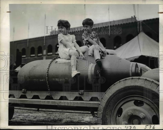 1942 Press Photo Mona and Marcus Reidenberg sit atop Aerial Bombs at War Show - Historic Images