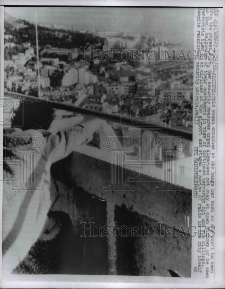 1962 Press Photo Woman Crouches as she hangs laundry - Historic Images