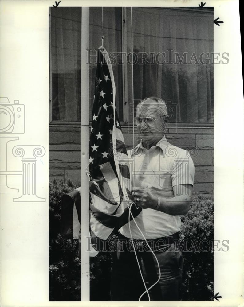 1985 Press Photo George Quellette raises the American flag in front of his house - Historic Images