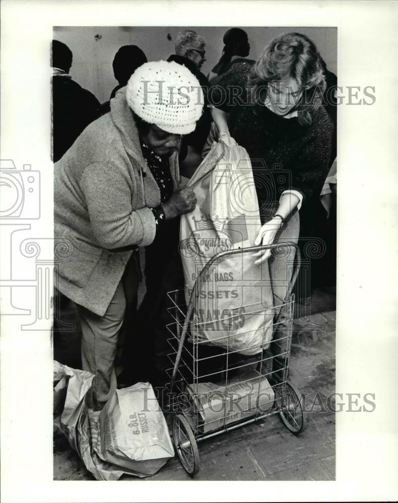 1985 Press Photo Meg Lilia &amp; West side resident load free food in her cart - Historic Images