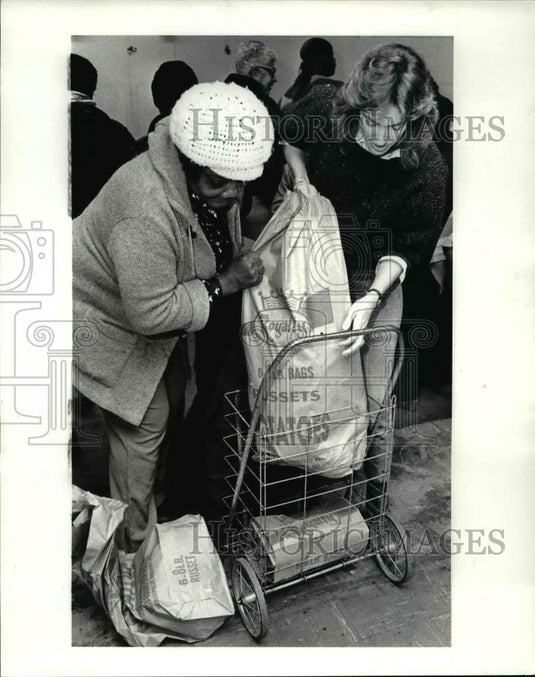 1985 Press Photo Meg Lilia & West side resident load free food in her cart - Historic Images