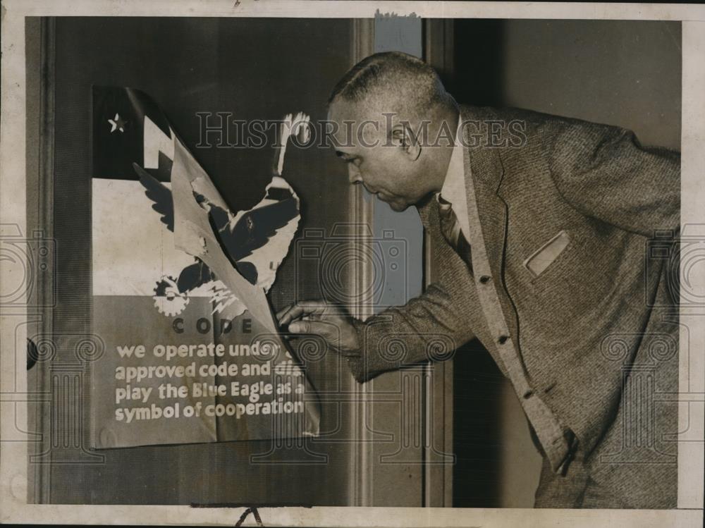 1935 Press Photo A man rips off a poster about the NRA off a door in Washington - Historic Images