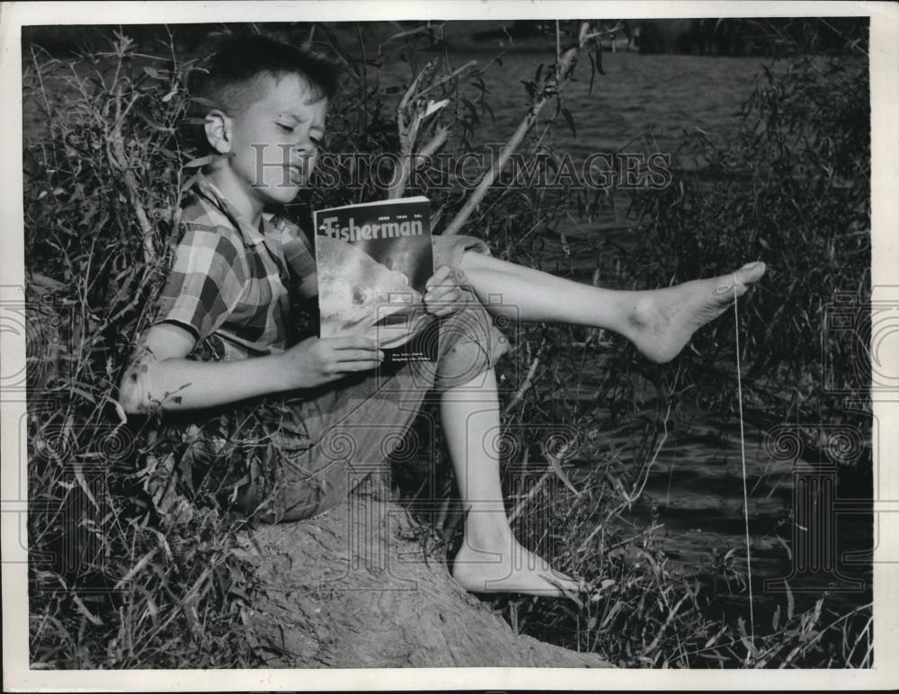 1954 Press Photo Roger Duane Caldwell is toe fishing while reading - Historic Images