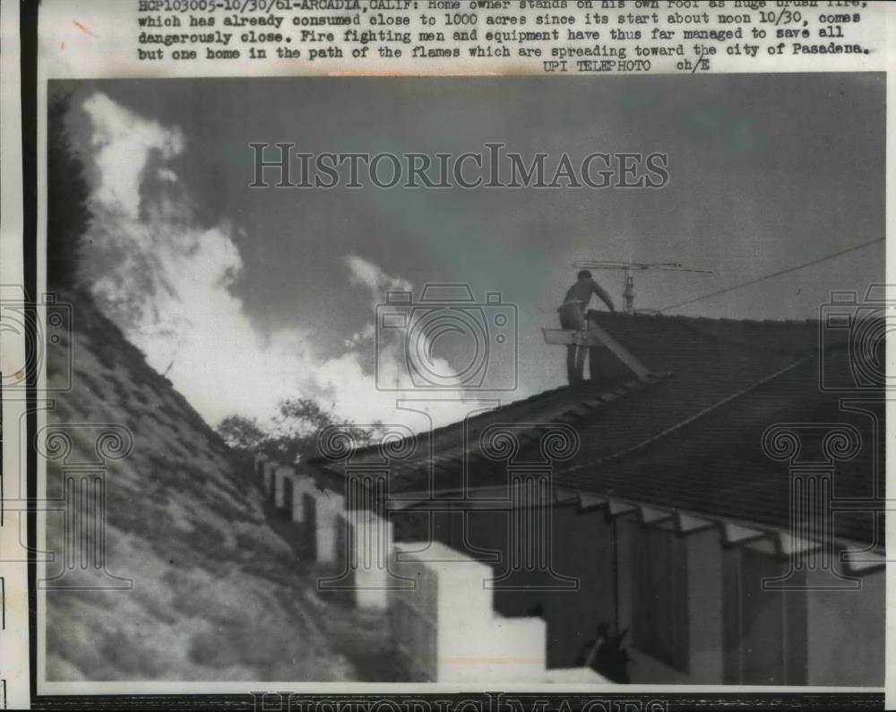 1961 Press Photo Homeowner stands on roof as brush fire comes close - Historic Images