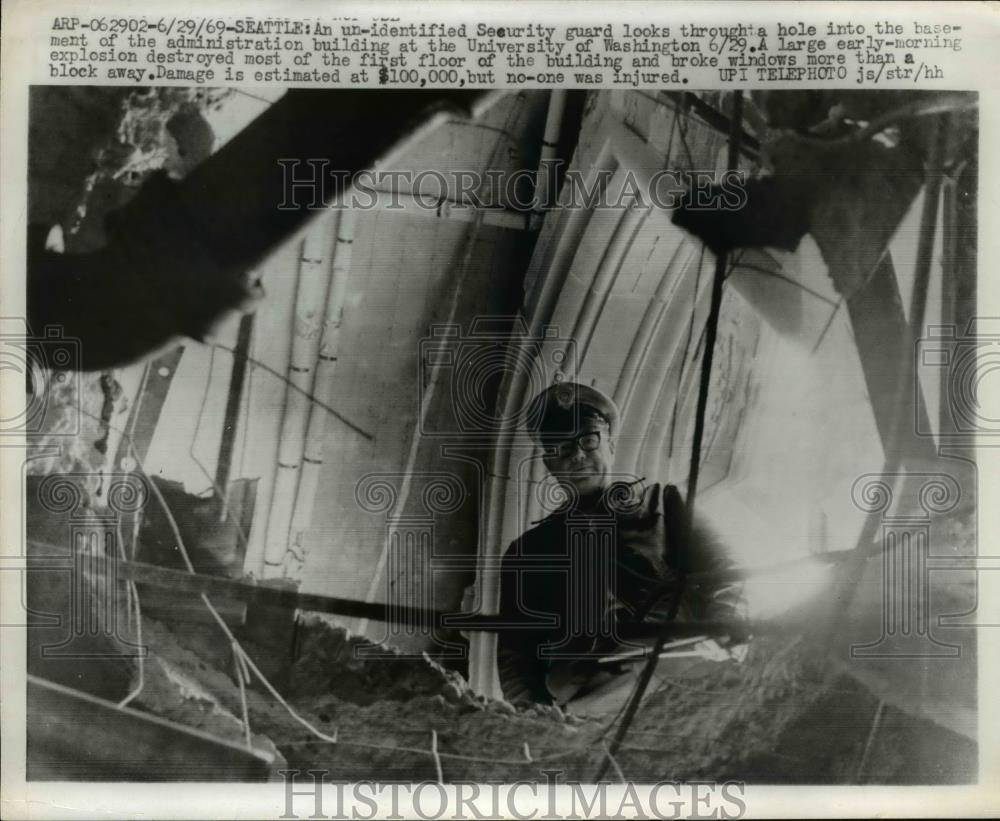 1969 Press Photo Settle Security guard looks through hole caused by explosion - Historic Images