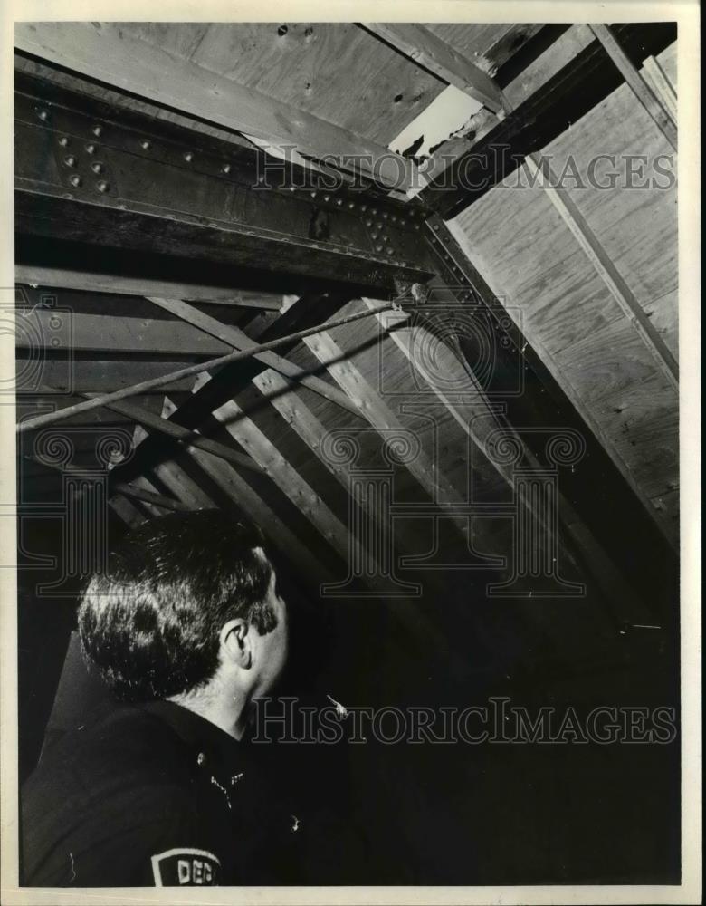 1975 Press Photo Chief Deputy Richard Amiott looks through hole in roof. - Historic Images