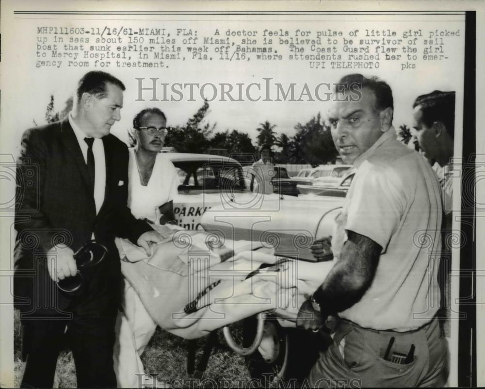 1961 Press Photo A doctor check girl survivor of sunken boat at Miami Florida - Historic Images