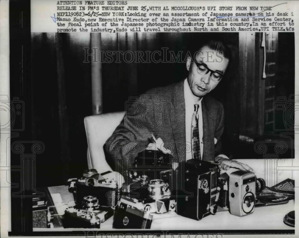 1959 Press Photo Masao Kudo assorting Japanese Cameras on hid desk. - nee85333 - Historic Images