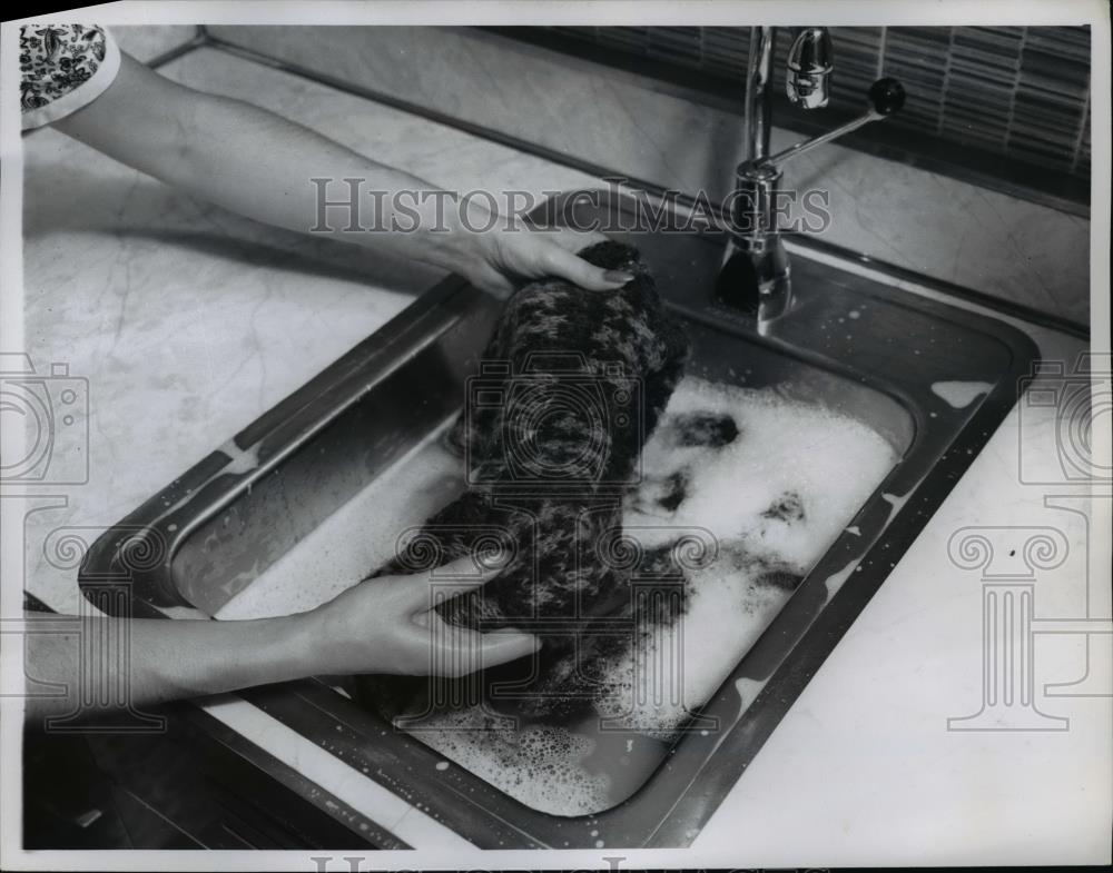 1960 Press Photo A sweater being hand laundered in a kitchen sink - nee84035 - Historic Images