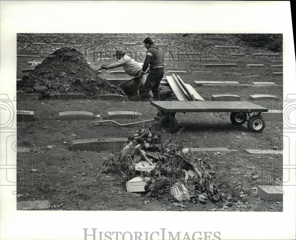 1986 Press Photo Carmen Pinzone &amp; Paul Brack cover a grave at Lakeview Cementery - Historic Images