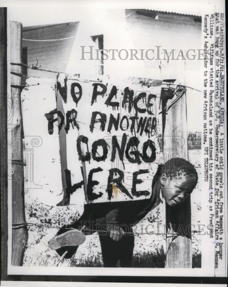 1961 Press Photo Girl crawls on the banner hung for arrival of G.Mennen William - Historic Images