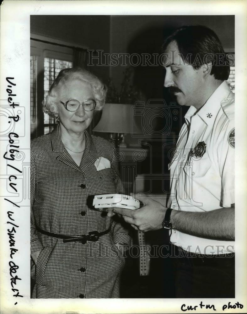 1984 Press Photo Richard Davis, shows Violet Colby how the smoke detector works - Historic Images