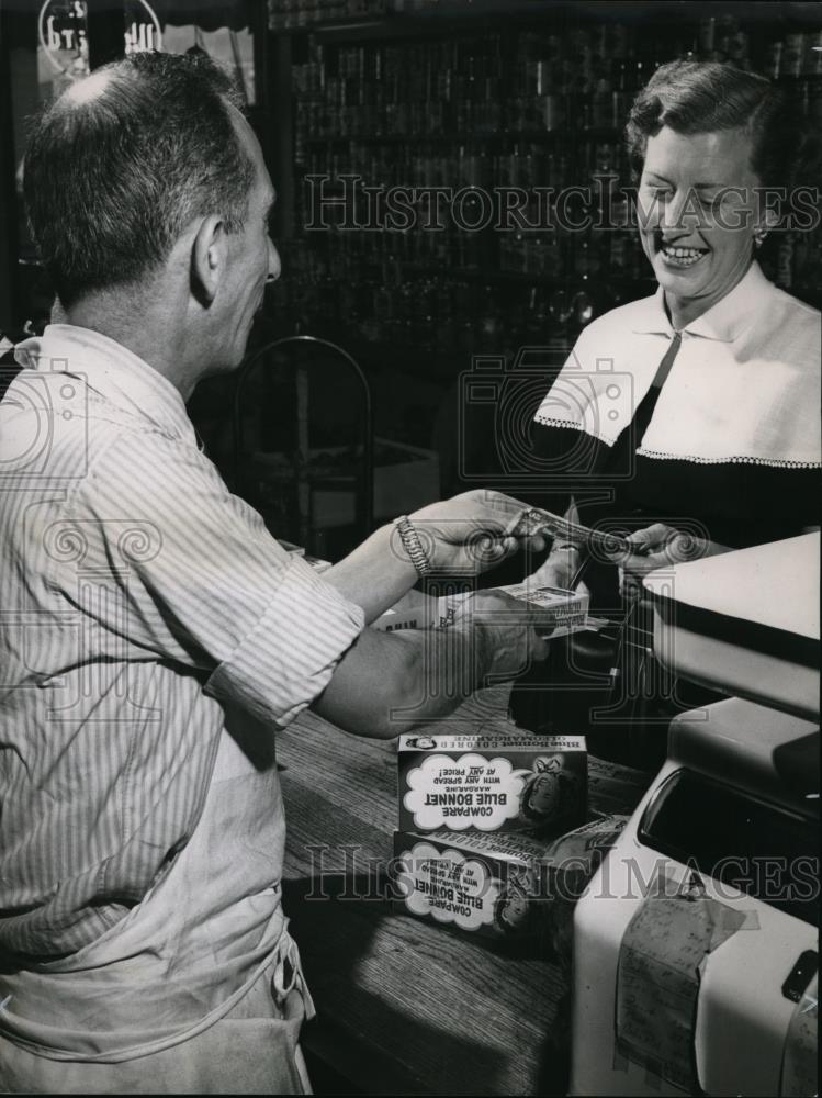 1951 Press Photo Grocer David Beres hands Mrs. Henry Becker the package. - Historic Images