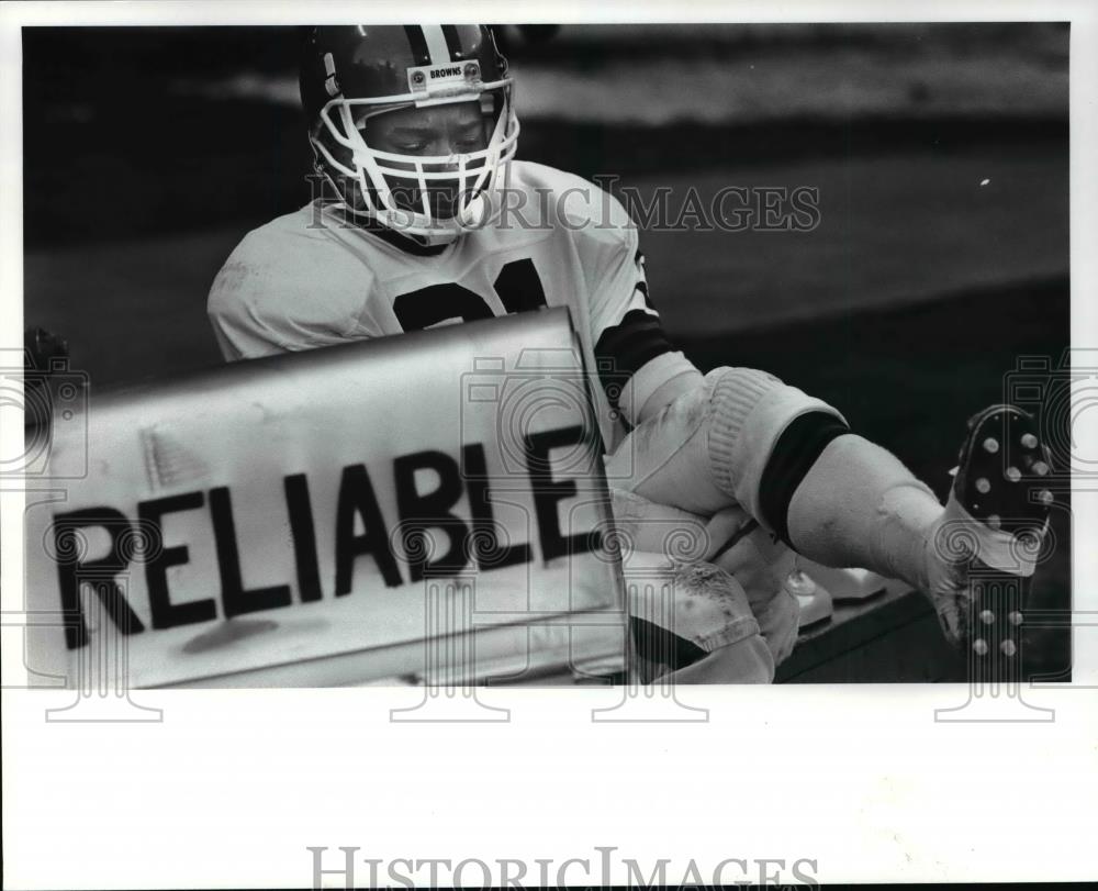 1986 Press Photo Frank Minnifield warms his feet by the heater on the sidelines - Historic Images