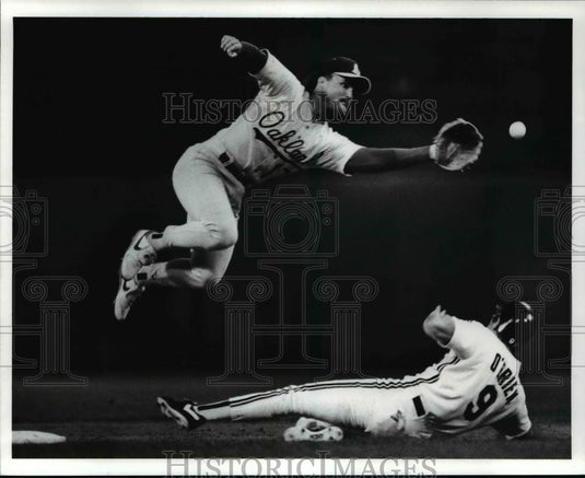 1989 Press Photo Pete O' Brien slides safely as a throw to Glenn Hubbard sails - Historic Images