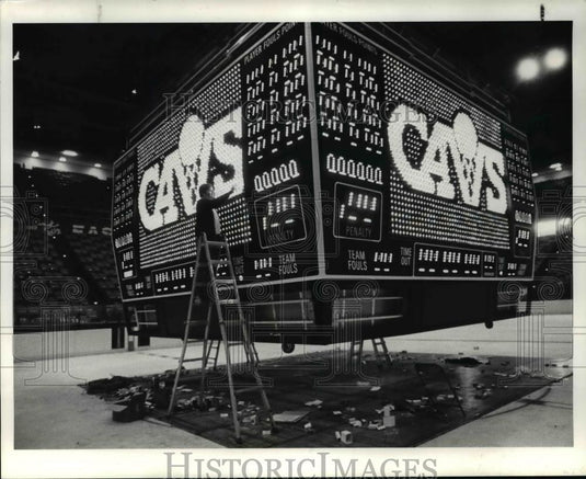 1984 Press Photo Workman adjusts lights on Cavaliers' 4 color scoreboard - Historic Images