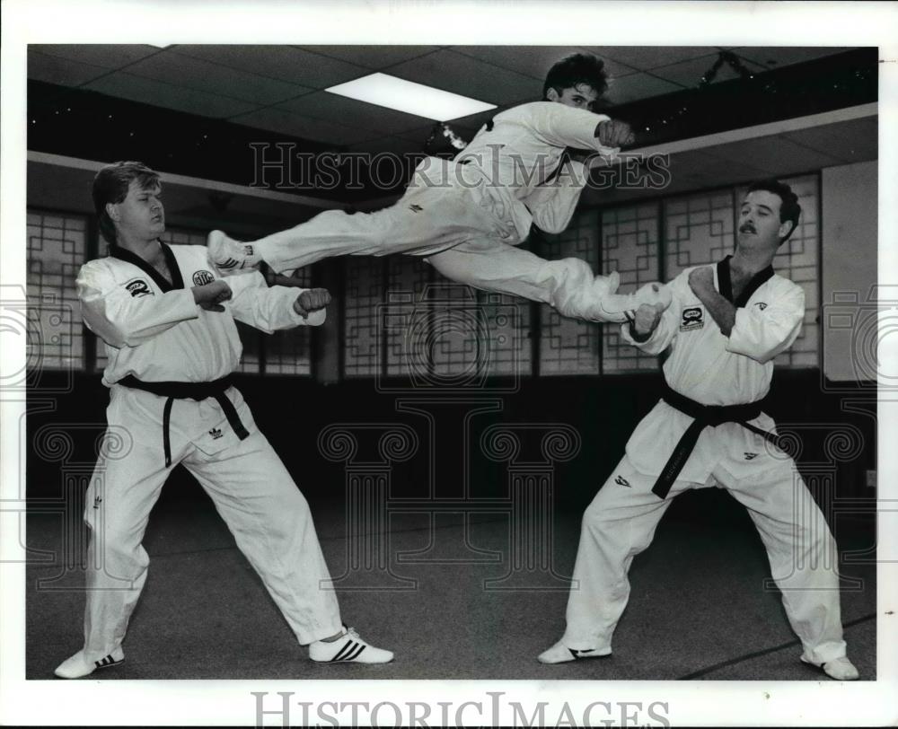 1991 Press Photo Joe E. Kim, Jumps up between: (L) Andrew Sokol, &amp; John Williams - Historic Images