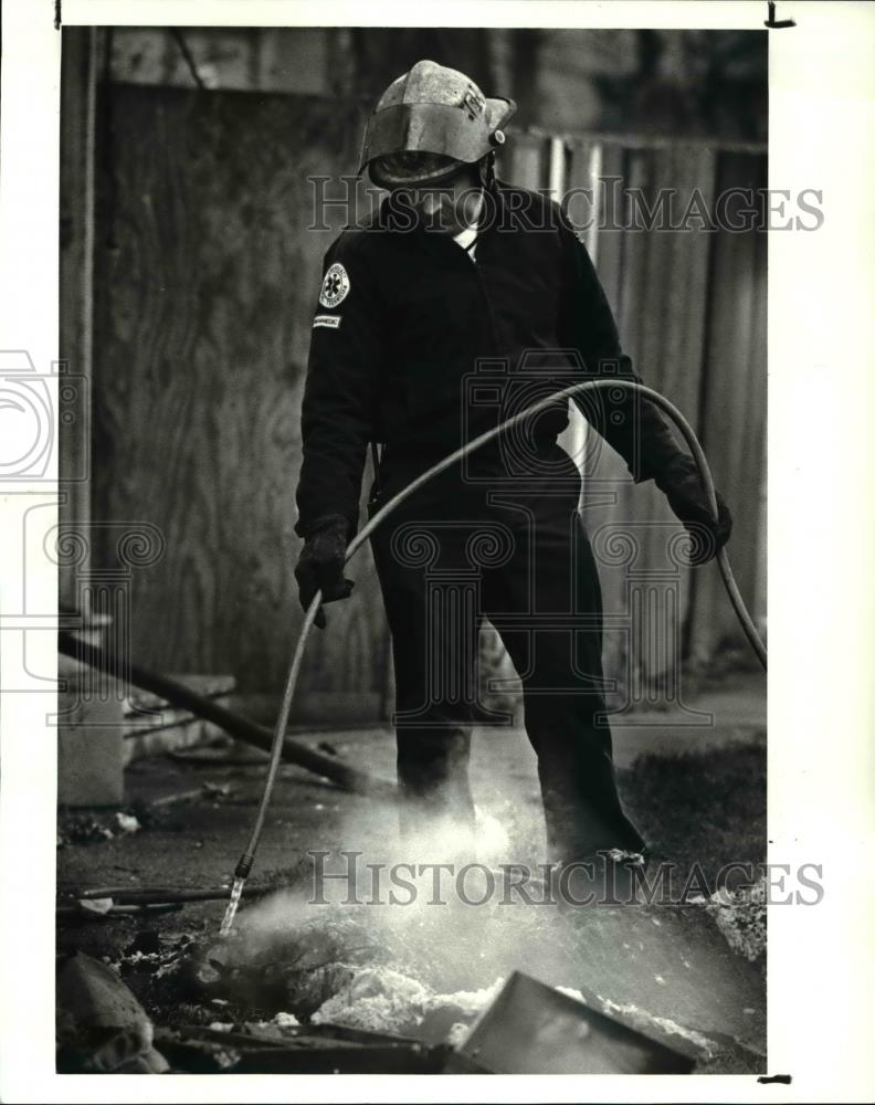 1987 Press Photo Cleveland firefighter Joe Mason extinguish debris from W. 47th - Historic Images