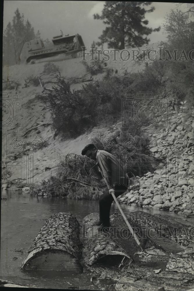 1942 Press Photo Worker rolling timber to water's edge of the Coulee Dam Lake - Historic Images