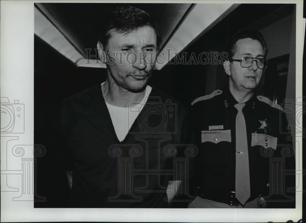 1987 Press Photo Raymond Bryton, murder suspect escorted by police officer - Historic Images