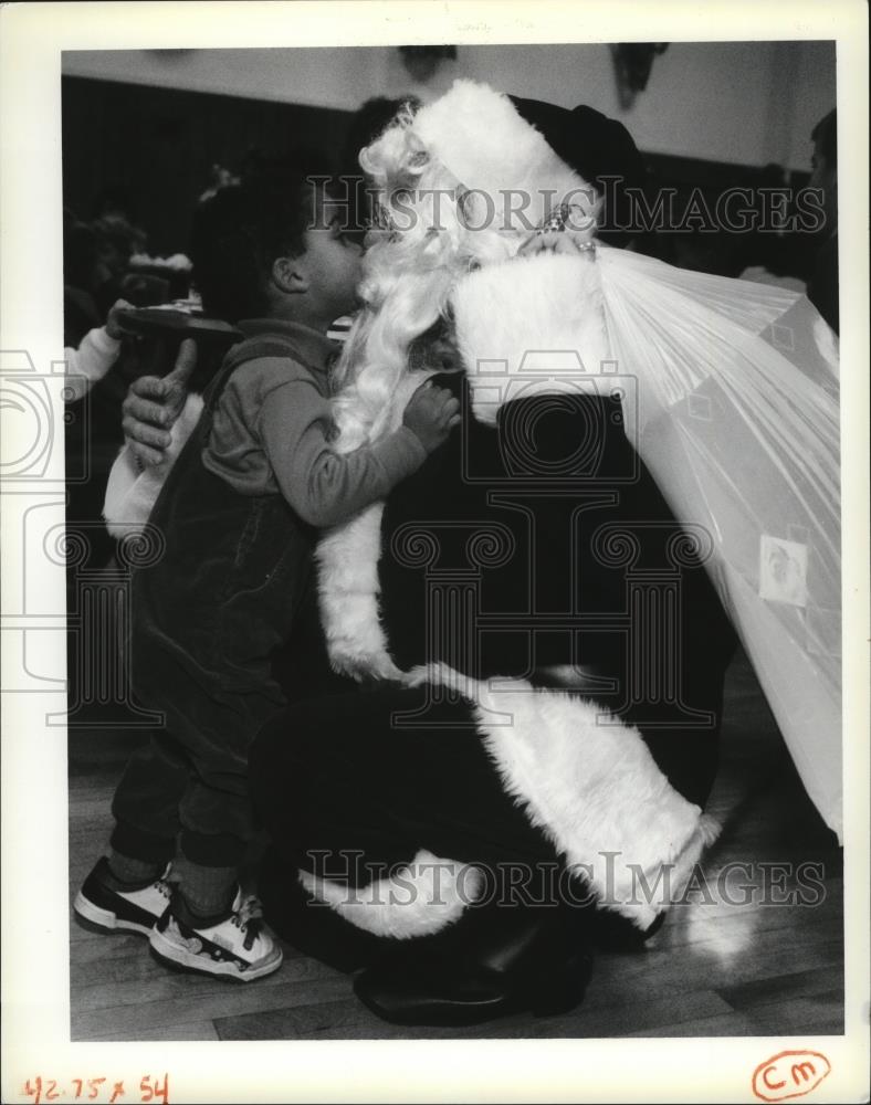 1991 Press Photo Little Adam Jarrell gives Santa Claus a kiss at Christmas Party - Historic Images
