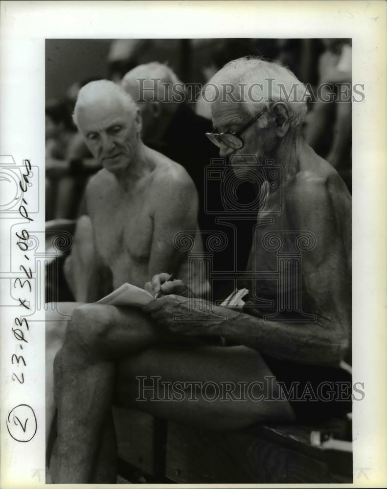 Press Photo Roy Webster checking his schedule while preparing to swim - Historic Images