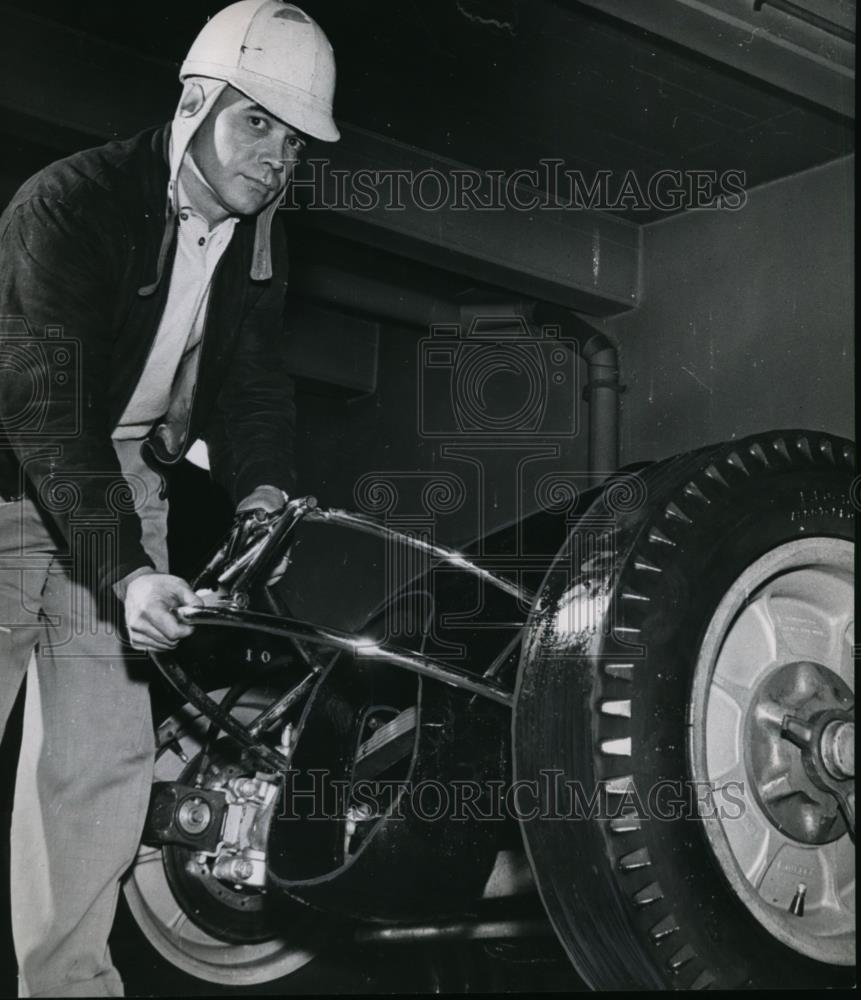 1957 Press Photo Frankie McGowan, veteran midget driver, puts bumper on race car - Historic Images