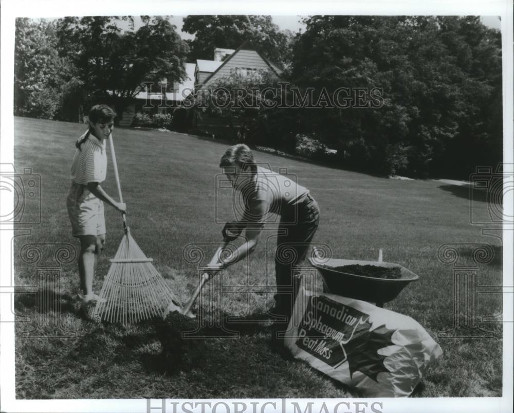 1990 Press Photo Father and daughter cleaning up their lawn - spa55334 - Historic Images