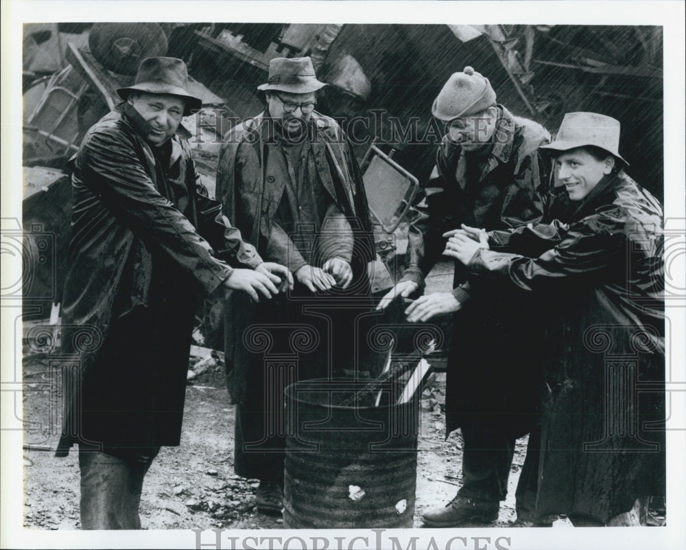 Press Photo Four Actors gather around a fire in a barrel in Scene from movie - Historic Images