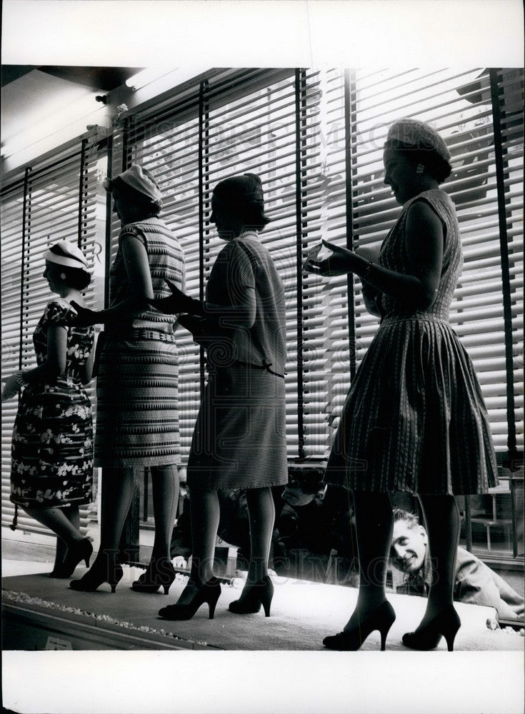 Women model dresses in shop window  - Historic Images