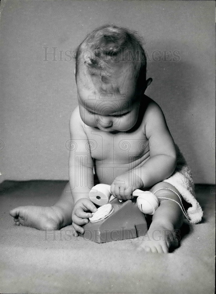  A baby playing with a toy phone - Historic Images