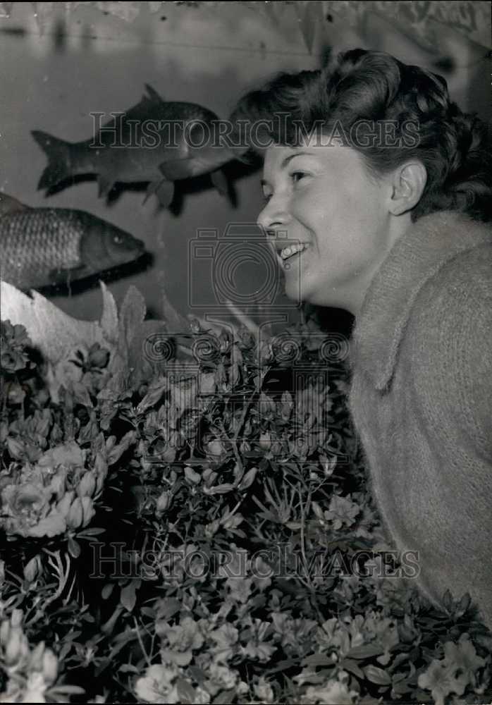 1960 Woman Observes Azaleas While Fish Swim in Giant Tank - Historic Images
