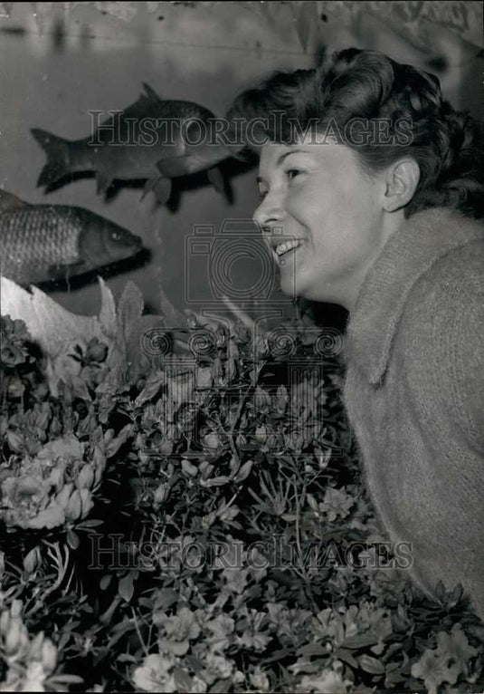 1960 Woman Observes Azaleas While Fish Swim in Giant Tank - Historic Images