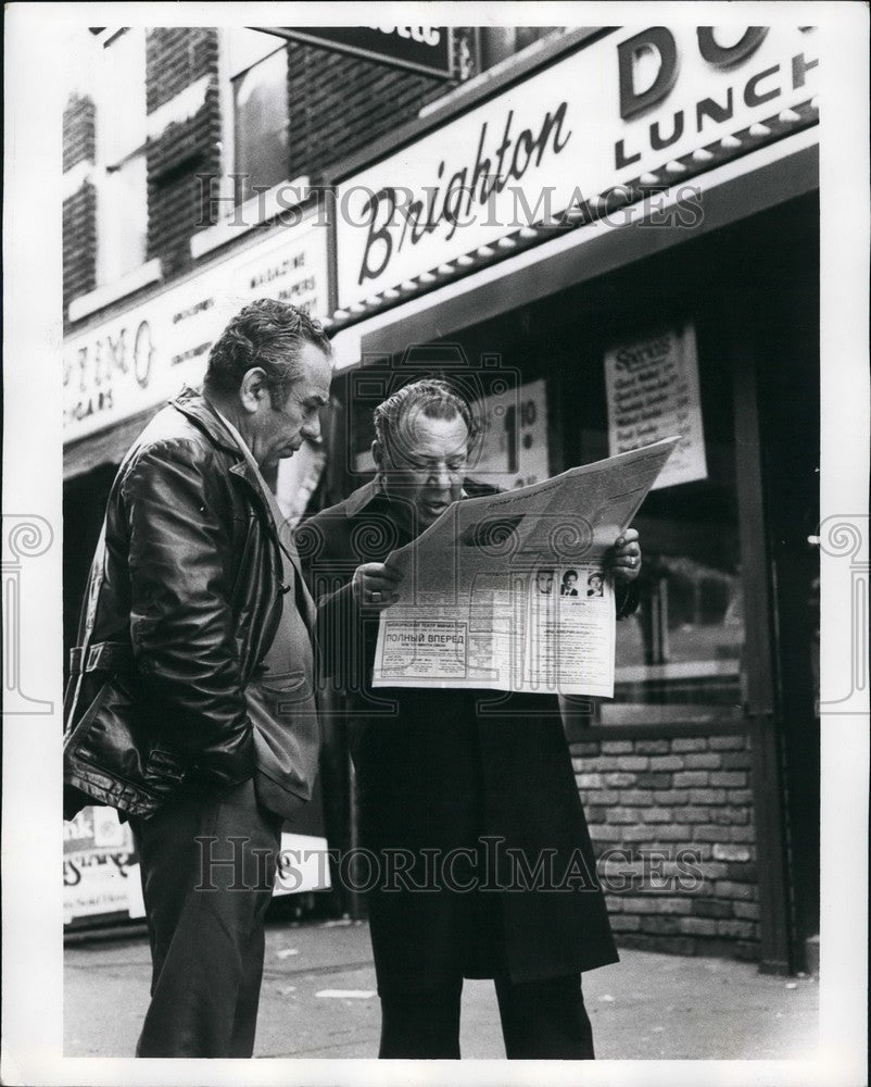 Press Photo two men looking at newspaper outside of Brighton building-Historic Images