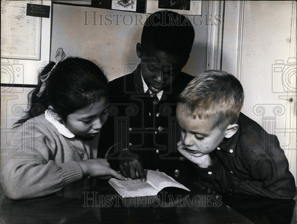 Press Photo Three Children Study A Book Together - Historic Images