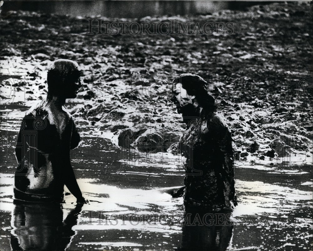 1973, Australia Mud cased figures larking around in a Sydney mud pool - Historic Images