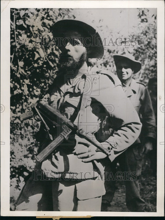 Press Photo Armed Man Walks Through Shrub Filled Area Followed By Other-Historic Images