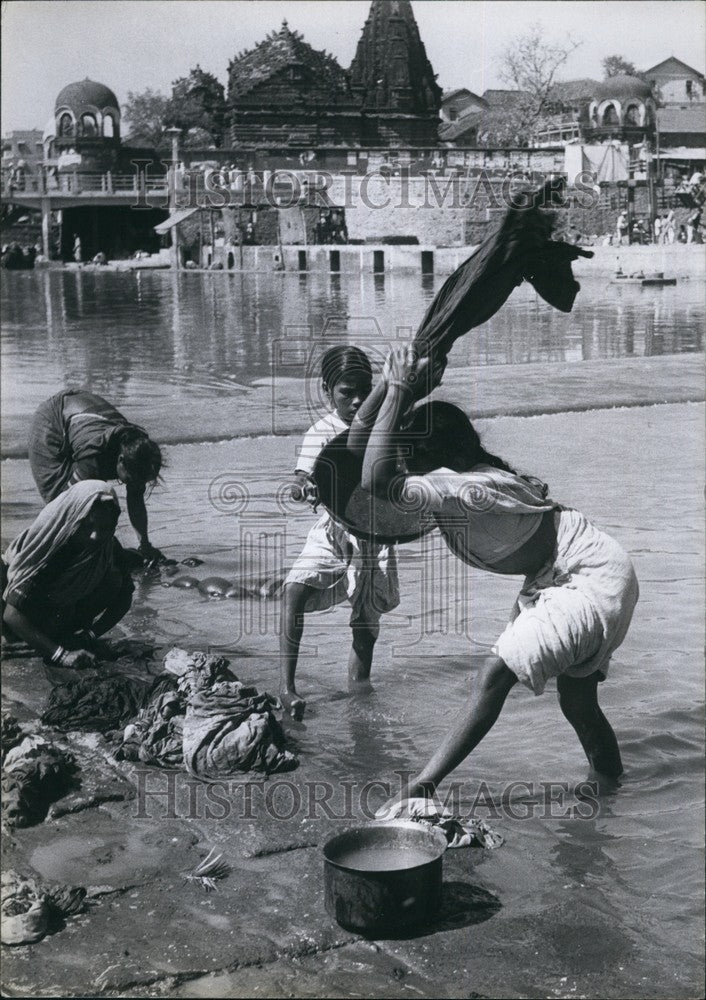 Press Photo Indian girls earn money washing clothes in the river - Historic Images