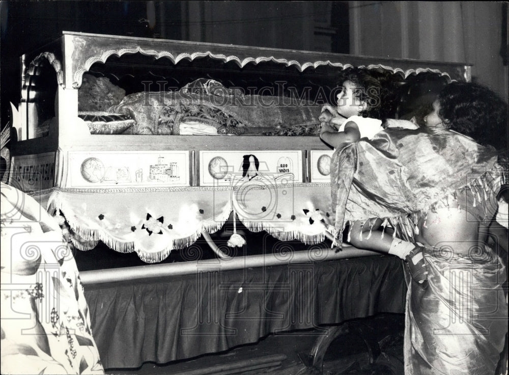 A baby is lifted to the glass tomb to see the miracle-Historic Images