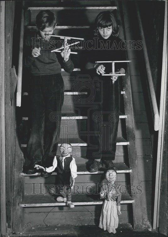 Press Photo Children play with dolls "Wirt und Wirten" on steps of workshop. - Historic Images