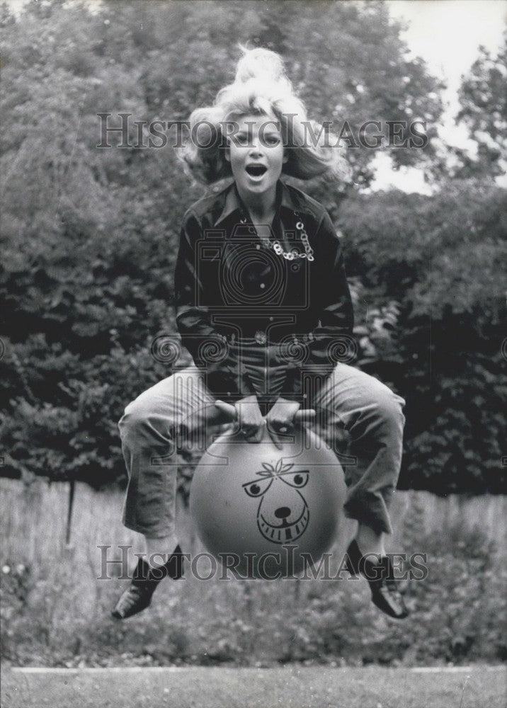 1968 Uta Levka on a kangaroo ball in her garden.  - Historic Images